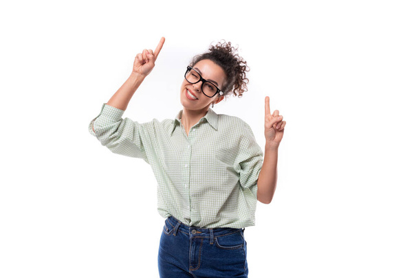 joven líder de éxito mujer con el pelo negro rizado en gafas se viste con una camisa sobre un fondo blanco. - Foto, imagen