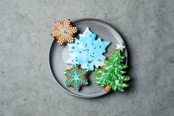 Perníkové sušenky ve tvaru vločky a vánoční stromeček na talíři na šedém pozadí. - Fotografie, Obrázek