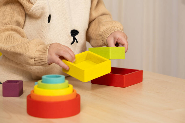 Niño jugando con juguetes Montessori multicolores de madera. Primer plano de las manos. - Foto, imagen