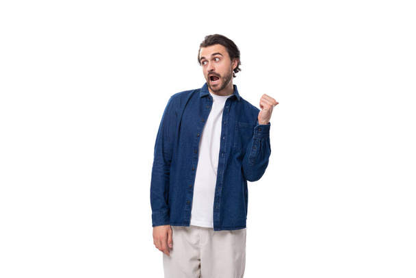 Avrupalı esmer, havalı saç stili olan genç bir adam tişörtünün üstüne mavi kot gömlek giymiş.. - Fotoğraf, Görsel