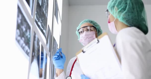 Médicos con gafas y máscaras mirando rayos X en la clínica 4k película cámara lenta. Diagnóstico por rayos X de neumonía en el concepto pandémico de covid19 - Metraje, vídeo