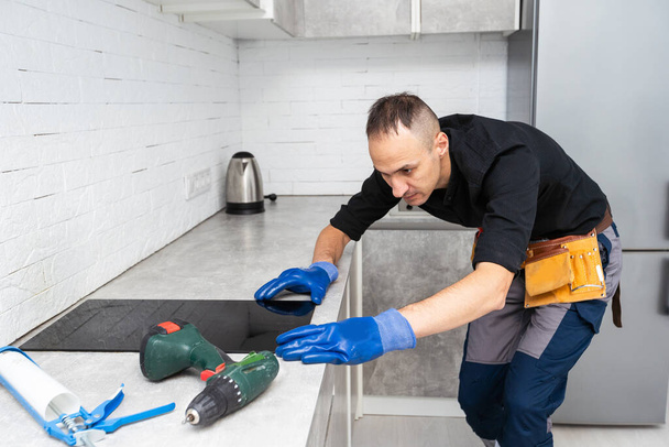 Handwerker installiert Kochfeld in Küche Konzept für die Installation von Haushaltsgeräten. Hochwertiges Foto - Foto, Bild
