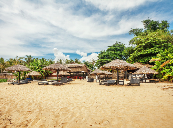 Wooden chairs and umbrellas on sand beach  - Фото, зображення
