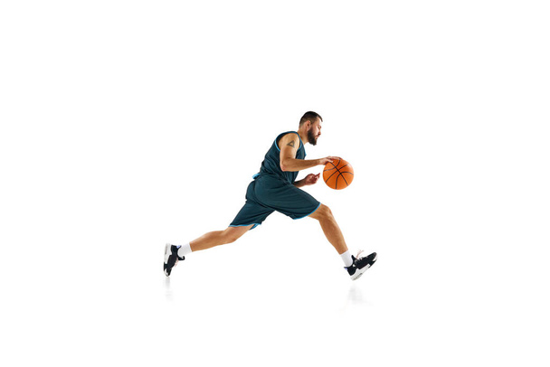 Dynamic, energetic portrait of sportsman, basketball player training slam dunk technique against white background. Concept of sport, hobby, active lifestyle, power and strength. Copy space, ad - Photo, Image