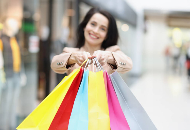 Woman holding many multicolored paper shopping bags in store closeup. Black friday sale concept - Photo, Image