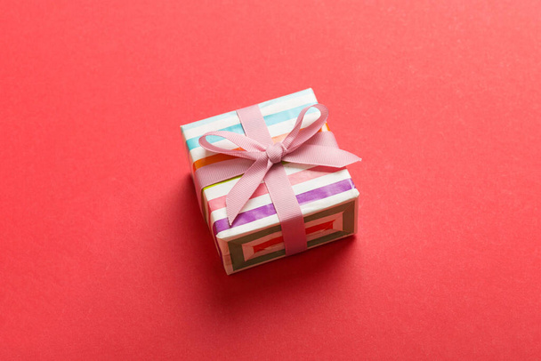 wrapped Christmas or other holiday handmade gift box in color paper with ribbon on colored background. Present box, decoration of gift on colored table, top view with copy space. - Photo, Image