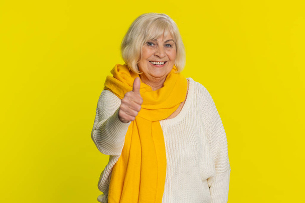 Like. Senior woman raises thumbs up agrees with something, gives positive reply recommends advertisement likes good idea feedback celebrating success victory. Grandmother isolated on yellow background - Photo, Image