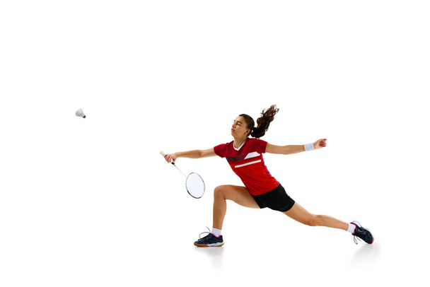 Atletiek en vastberadenheid. professionele vrouwelijke badminton speler training in beweging tegen witte studio achtergrond. Concept van sport, actieve levensstijl, kracht en kracht, actie. Kopieerruimte. - Foto, afbeelding