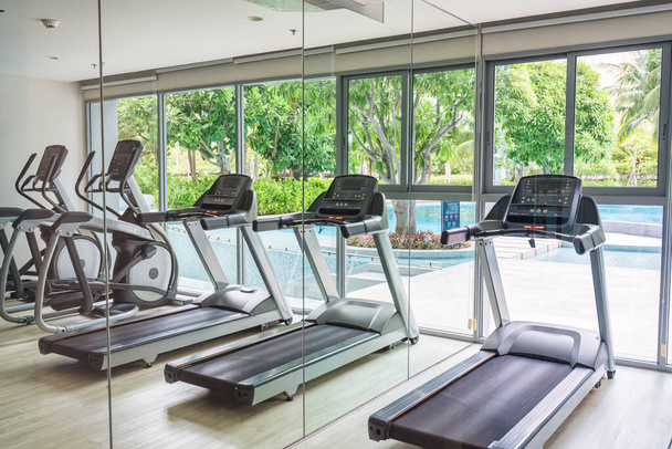 Row of nobody treadmill machine and glass window with garden view in fitness gym - Photo, Image