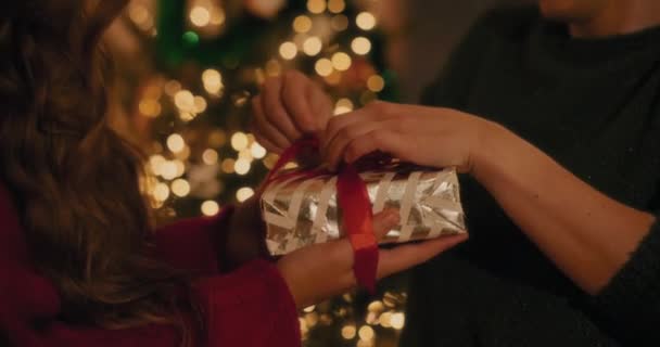 Sección media del hombre atando cinta en regalo de Navidad en poder de una amiga en casa - Imágenes, Vídeo