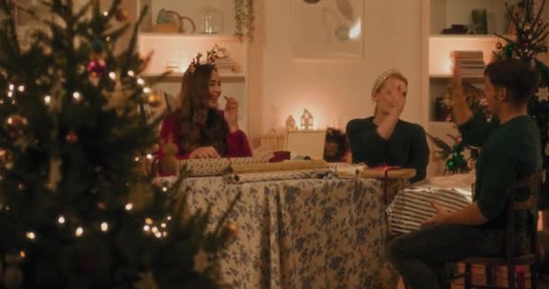 Joven macho y hembra amigos dando cinco altos mientras se sienta en casa durante las vacaciones de Navidad - Imágenes, Vídeo