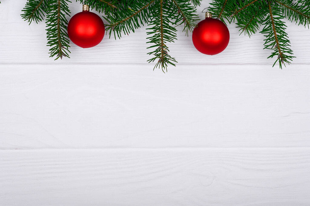 Χριστουγεννιάτικο φόντο με κλαδιά χριστουγεννιάτικου δέντρου, μπάλες και διακοσμήσεις σε λευκό ξύλινο τραπέζι, πάνω όψη, χώρος για κείμενο. - Φωτογραφία, εικόνα