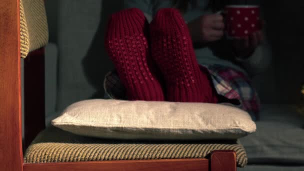 Femme met les pieds dans des chaussettes de Noël confortables avec tasse de café moyen 4k slow motion mise au point sélective - Séquence, vidéo