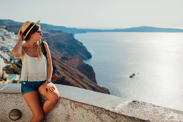 Mujer turista disfrutando del paisaje marino de Caldera en Fira, isla de Santorini, con vistas al mar y a la montaña. Viajar durante las vacaciones de verano - Foto, Imagen