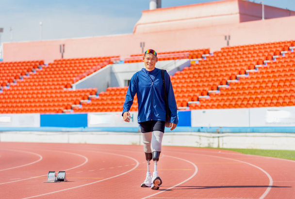 Sport man athlete prosthesis legs carry the bag and walk on the track of the stadium with day light and happiness. - Photo, Image