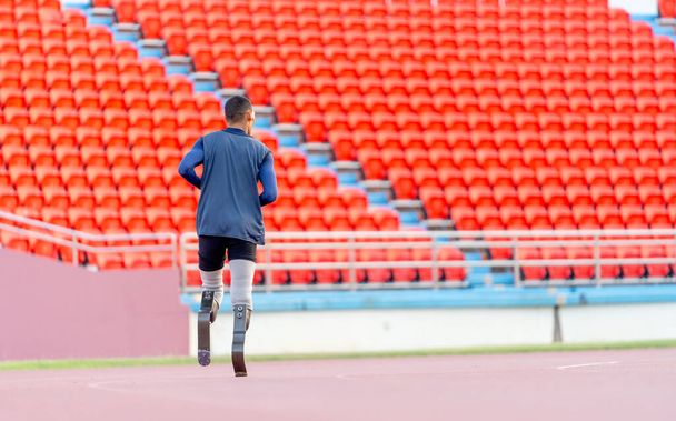 Brede terugslag van sportman atleet prothese benen lopen of joggen in de baan van het stadion met daglicht. - Foto, afbeelding