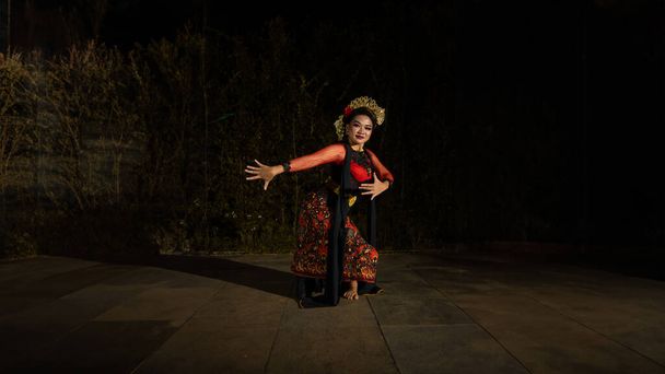 Μια Ασιάτισσα χορεύτρια χορεύει μπροστά στην αυλή φορώντας κόκκινη στολή τη νύχτα. - Φωτογραφία, εικόνα