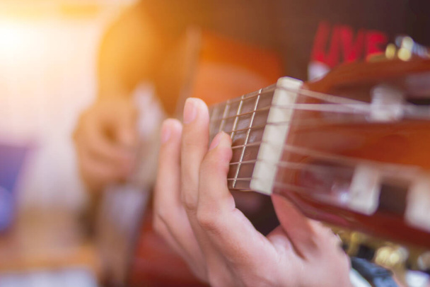 Nuori mies harjoittelee kitaransoittoa musiikkiharjoitushuoneessa ennen esiintymistä vähentääkseen virhettä soittaa kitaraa lavalla. Close Up Young mies pitää kitarasointuja harjoituksissa. - Valokuva, kuva