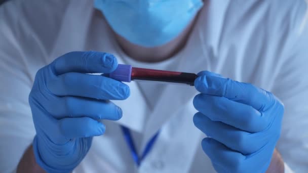 Arzt hält Labor-Reagenzglas mit Blut markiert und markiert Coronavirus COVID-19. 2019-nCoV Coronavirus. Positive Blutprobe in der Hand der Ärzte mit Handschuhen. Analyse im Forschungslabor. - Filmmaterial, Video