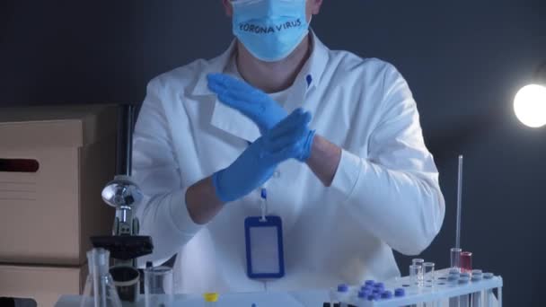 Wissenschaftler im Chemielabor zeigt verbotene Geste mit den Händen. Der Arzt mit der Maske und dem Wort Coronavirus auf dem Kopf ist es leid, nach einem Impfstoff zu suchen und die Behandlung von Covid 19 zu erfinden. E-Krise. - Filmmaterial, Video