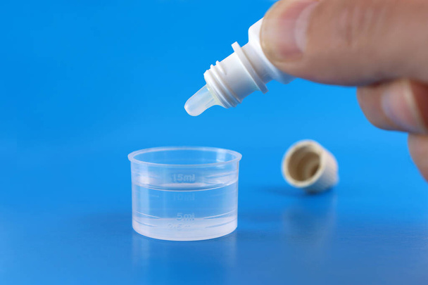La solución medicinal se prepara goteando el medicamento en una taza dosificadora con agua. Tratamiento y prevención de la salud. - Foto, Imagen