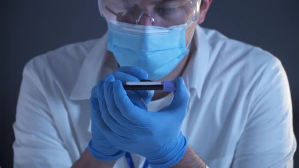 El médico sostiene la sonda de laboratorio con el coronavirus marcado y etiquetado con sangre COVID-19. 2019-nCoV Coronavirus. Muestra de sangre positiva en los médicos mano con guantes. Análisis en laboratorio de investigación. - Metraje, vídeo