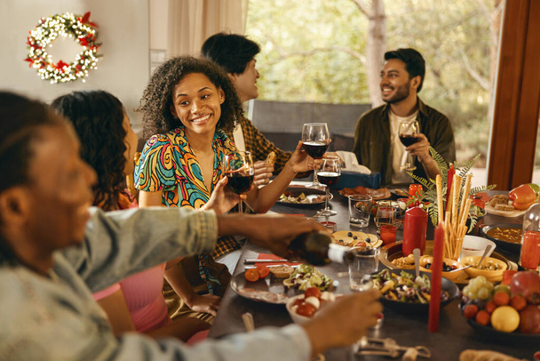 Grupo de jovens amigos felizes está bebendo vinho ao ter férias jantar em casa festa juntos - Foto, Imagem
