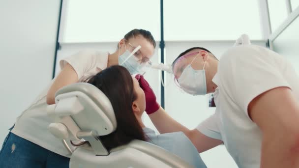 Kontrola stomatologiczna w nowoczesnej klinice, stomatologa i asystenta wykonującego badania stomatologiczne pacjenta - Materiał filmowy, wideo