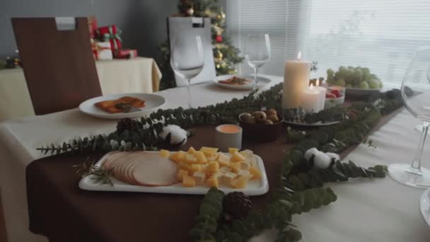 Medio primer plano de cubitos de jamón y queso, aceitunas, uva y otros aperitivos en la mesa festiva servida para la celebración de Navidad en casa - Metraje, vídeo