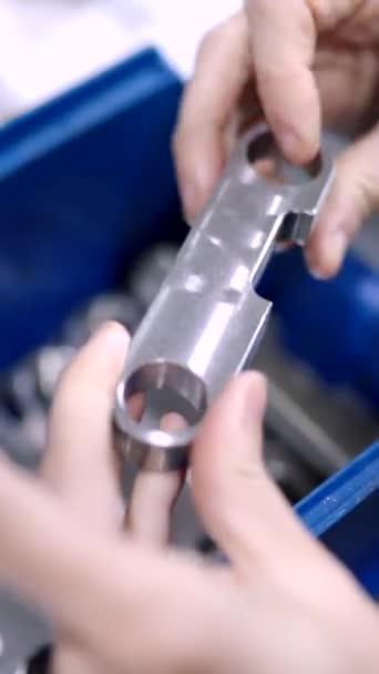 Video con el primer plano de las manos de un ingeniero que comprueba la calidad de pequeñas piezas de metal en una fábrica moderna cnc - Metraje, vídeo