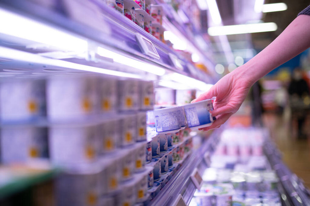 Woman picking up yogurt in a supermarket - Foto, immagini