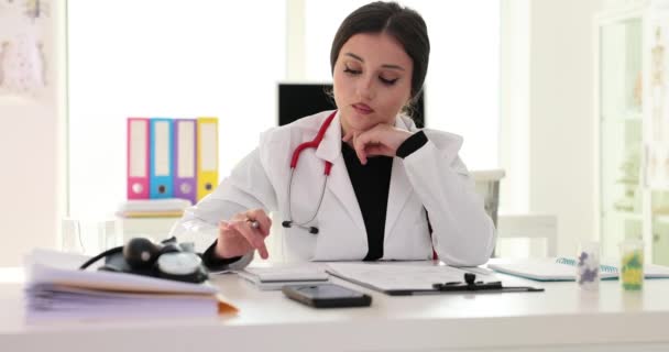 El médico calcula el costo de los servicios médicos utilizando la calculadora. Seguro de enfermedad - Imágenes, Vídeo