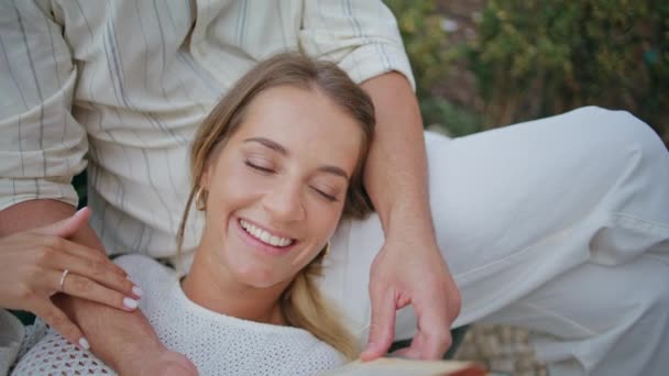 Smiling girlfriend enjoying book with unknown man at bench closeup. Handsome unshaven boyfriend holding novel reading aloud for loving woman. Brunette macho spending time with lady. Love concept - Footage, Video