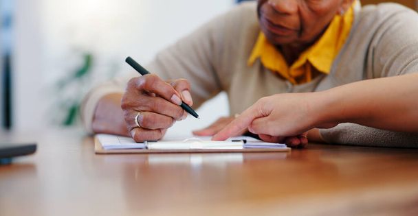 Oudere vrouw, handen en schrijven op contract, formulier of aanvraag voor pensioenregeling of verzekering thuis. Sluiten van oudere vrouwelijke personen die documenten, papieren of een overeenkomst op tafel thuis ondertekenen. - Foto, afbeelding