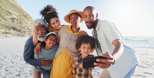 Selfie, abbraccio e famiglia felice in spiaggia per viaggiare, divertirsi o avventurarsi insieme nella natura. Amore, foto profilo e bambini africani con genitori e nonni al mare per estate, vacanza o viaggio. - Foto, immagini