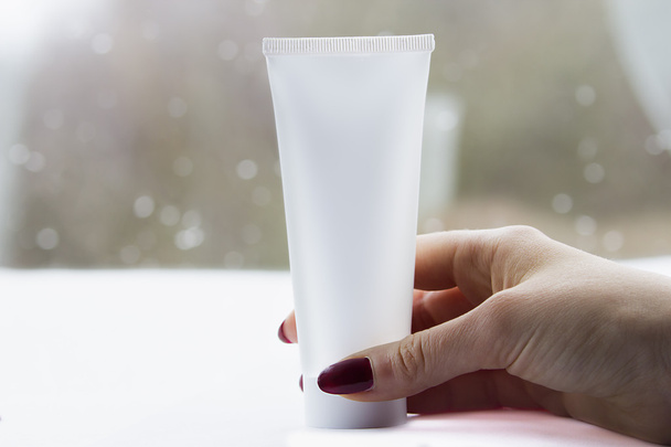 Woman hand with a white cream tube - Foto, afbeelding