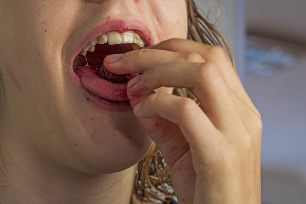 Девушка ест красную малину с широко раскрытым ртом - Фото, изображение