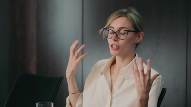 Professionelle Frau gestikuliert während der Rede, Engagierte Geschäftsfrau mit Brille gestikuliert mit ihren Händen, während sie im Büro spricht - Filmmaterial, Video