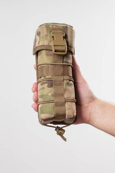 Homem segurando tampa protetora para tecido monocular, militar pixelado, caso isolado em fundo branco. - Foto, Imagem