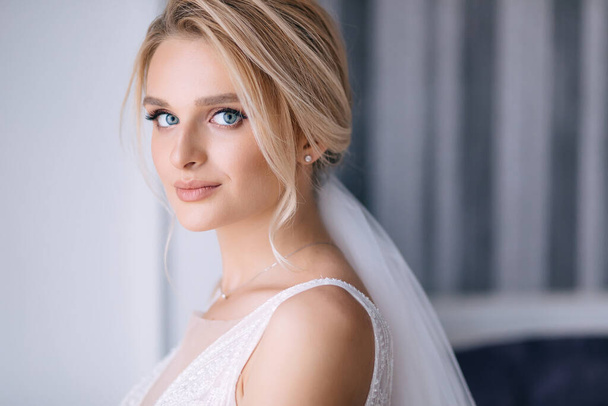 красива наречена з світлим волоссям в елегантній весільній сукні позує в кімнаті на весіллі вранці
 - Фото, зображення