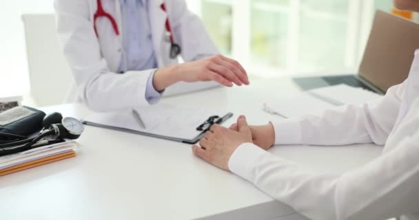 Amistosa doctora sosteniendo paciente mano en la clínica durante la cita. El resultado del examen es una prueba positiva y se calma. - Metraje, vídeo