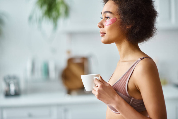 békés afro-amerikai nő szemkötőkkel áll fehérneműben és élvezi a reggeli kávét - Fotó, kép