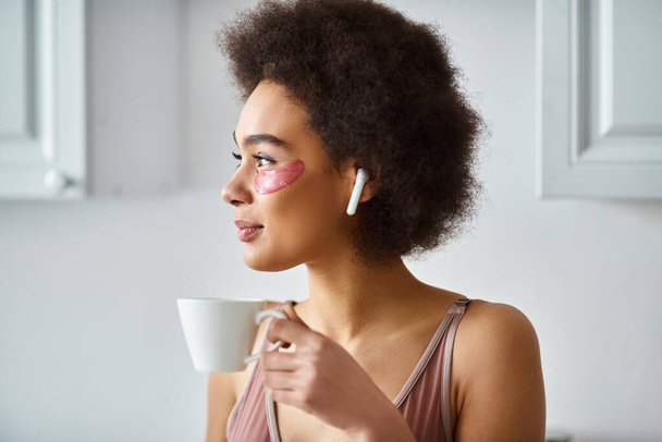 Spokojny moment z afrykańską Amerykanką w słuchawkach i bieliźnie sącząc poranną kawę, portret - Zdjęcie, obraz