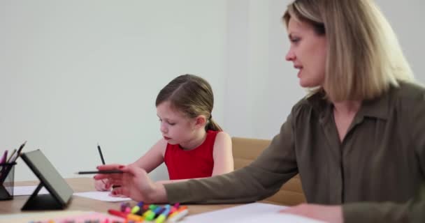 Professeure travaille en tête-à-tête avec une écolière en utilisant la tablette en gros plan. Enseigner aux enfants à dessiner - Séquence, vidéo