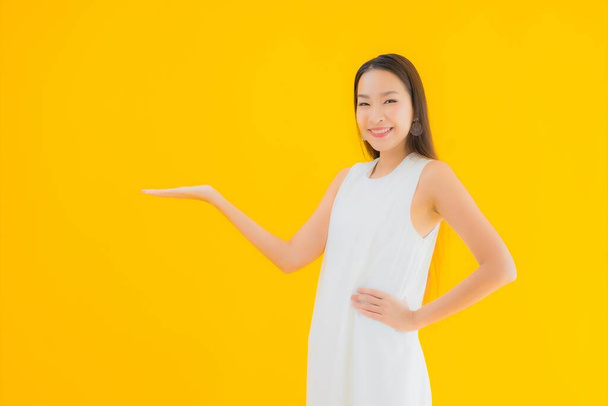 Retrato hermosa joven asiática mujer en acción sobre amarillo aislado fondo - Foto, Imagen