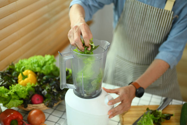 Gesunder Senior in Schürze bereitet veganen Bio-Smoothie in der Küche zu - Foto, Bild