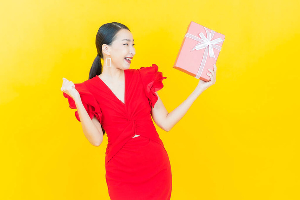Retrato hermosa joven mujer asiática sonrisa con caja de regalo roja sobre fondo de color - Foto, imagen