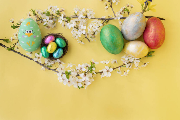 Oeufs colorés de Pâques et branches fleuries blanches de printemps sur fond jaune. Image plate avec espace de copie. douce carte lumineuse de Pâques - Photo, image