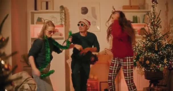 Vrolijke mannelijke en vrouwelijke vrienden hebben plezier tijdens het dansen samen thuis tijdens de kerstvakantie - Video