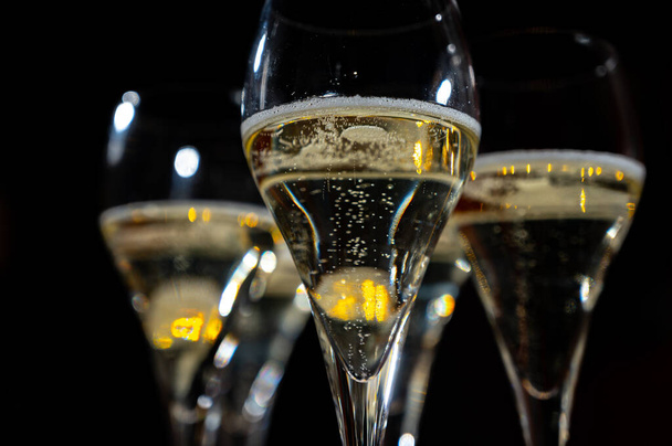 Fête du Nouvel An, petites bulles de champagne cava brut ou de vin prosecco dans des verres à tulipes avec guirlande sur fond sombre - Photo, image